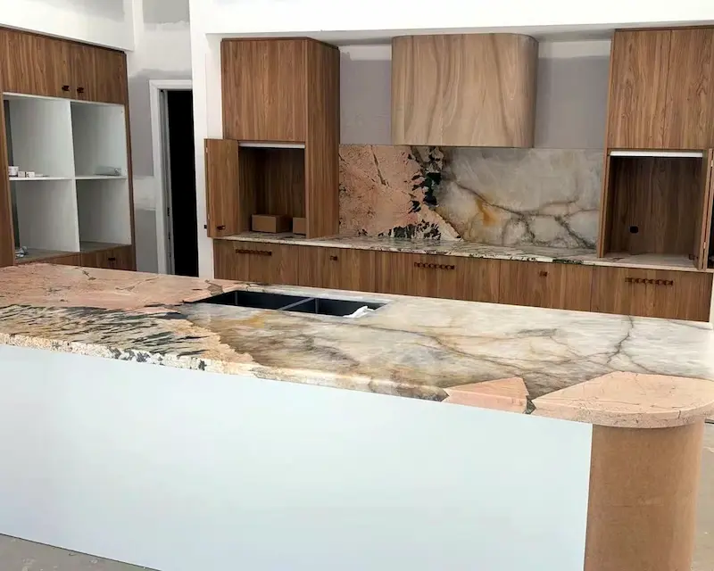 Finished natural stone kitchen countertop project with custom stone backsplash and island surface